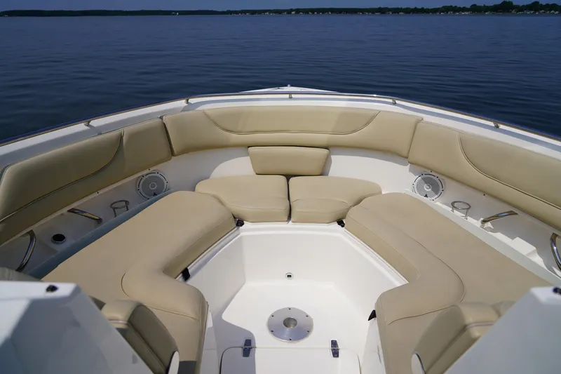Slide: The Image of The image shows the bow area of a Pursuit DC 325 Dual Console boat with beige cushions. - 38