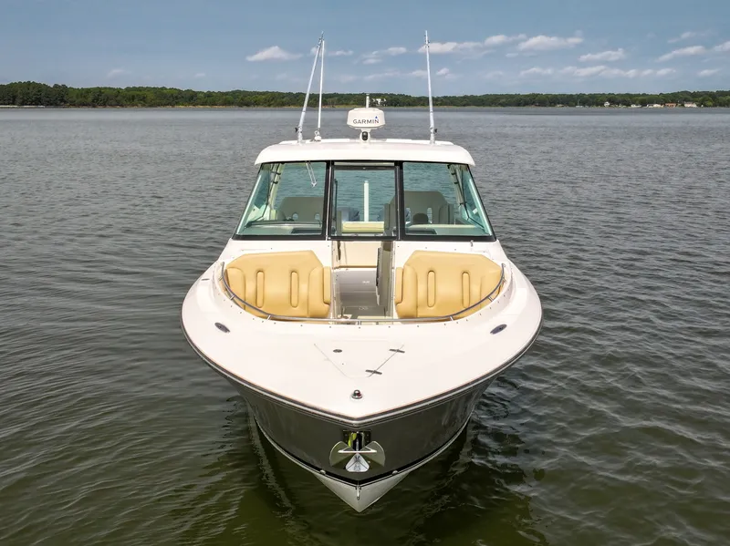 Slide: The Image of A 2015 Pursuit DC 325 Dual Console on calm water with a beige seating area. - 23