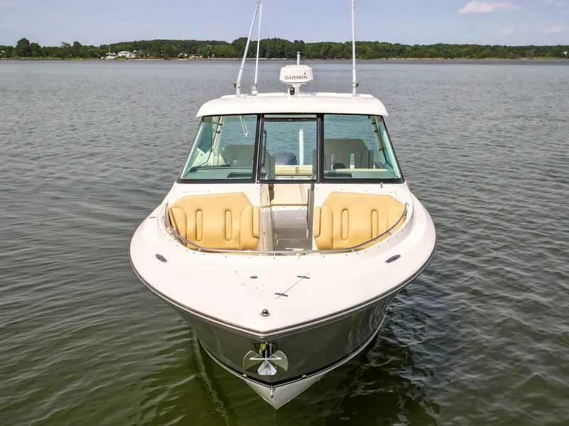 Slide: The Image of The 2015 Pursuit DC 325 Dual Console is seen on calm water. It features a sleek design with beige bow seating. - 26