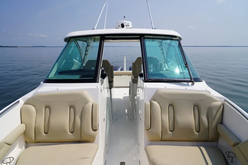 Slide: The Image of A 2015 Pursuit DC 325 Dual Console boat on calm water. It features beige upholstered seats and a clear windshield. - 41