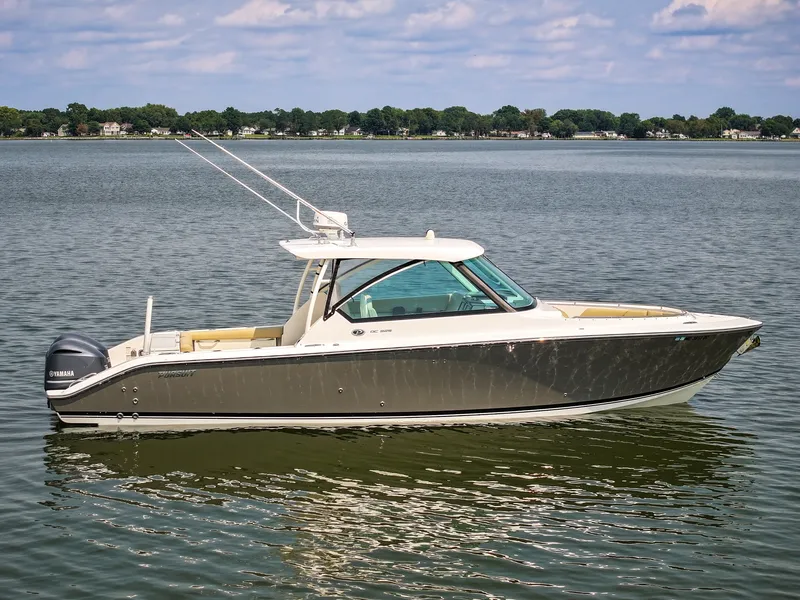 Slide: The Image of A 2015 Pursuit DC 325 Dual Console boat floats on calm water under a blue sky. - 7