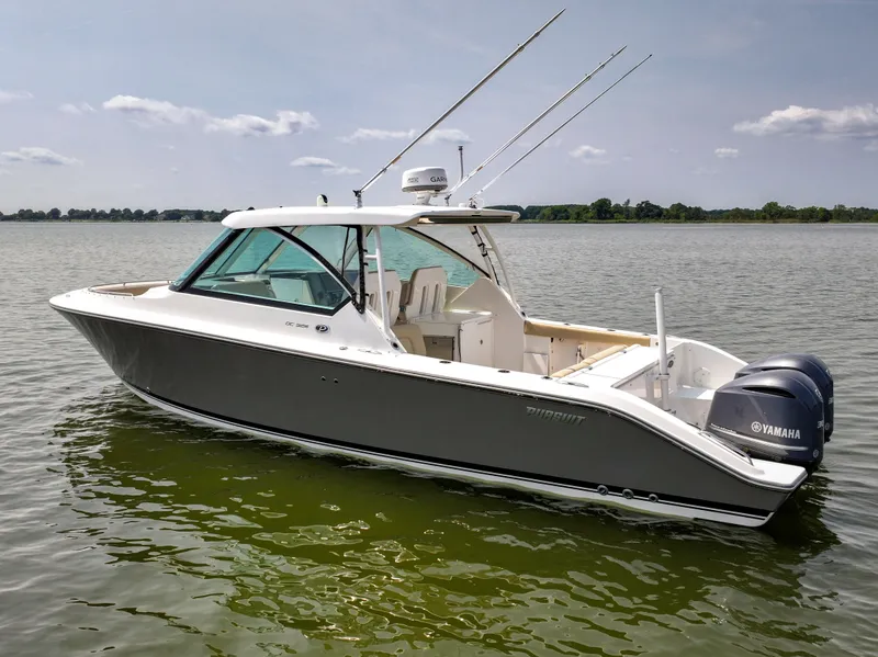 Slide: The Image of A 2015 Pursuit DC 325 Dual Console boat on calm water with twin outboard engines. - 16