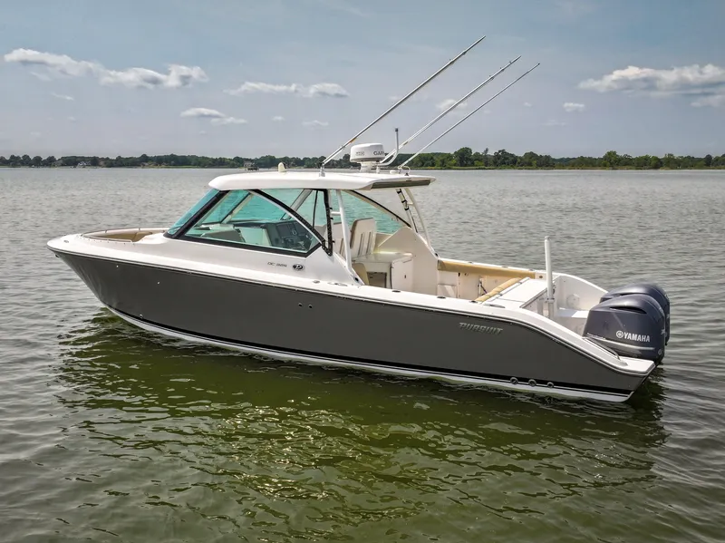Slide: The Image of A gray 2015 Pursuit DC 325 Dual Console boat floats on calm water under a clear sky. - 15