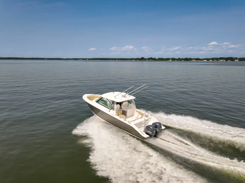 The Image of A 2015 Pursuit DC 325 Dual Console boat speeding across calm waters. - 1