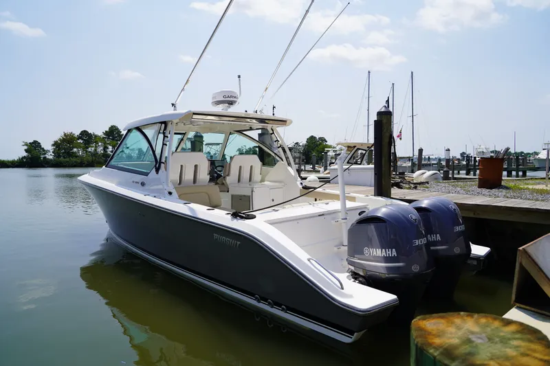 Slide: The Image of A 2015 Pursuit DC 325 Dual Console boat docked in calm waters, featuring twin Yamaha engines. - 32