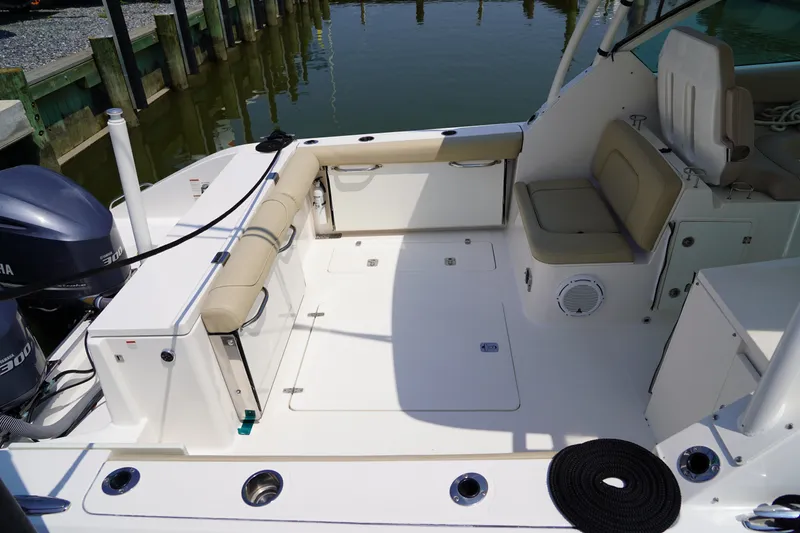 Slide: The Image of The image shows the cockpit of a 2015 Pursuit DC 325 Dual Console boat. It features beige upholstery and is docked. - 35