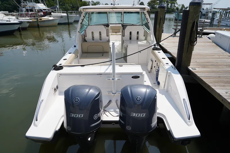 Slide: The Image of A 2015 Pursuit DC 325 Dual Console boat docked. It features two outboard engines. - 31