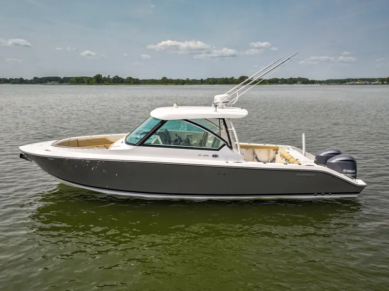 Slide: The Image of A 2015 Pursuit DC 325 Dual Console boat on calm water with two outboard engines. - 17