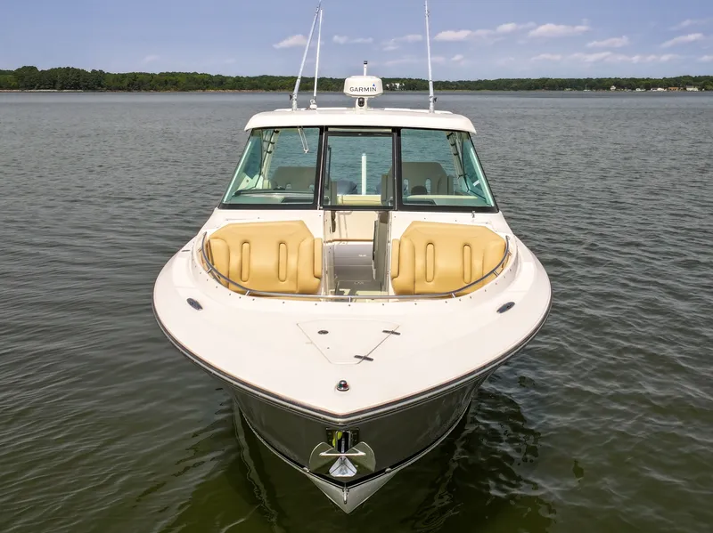 Slide: The Image of The 2015 Pursuit DC 325 Dual Console is seen on calm water, featuring cream upholstery and sleek design. - 24