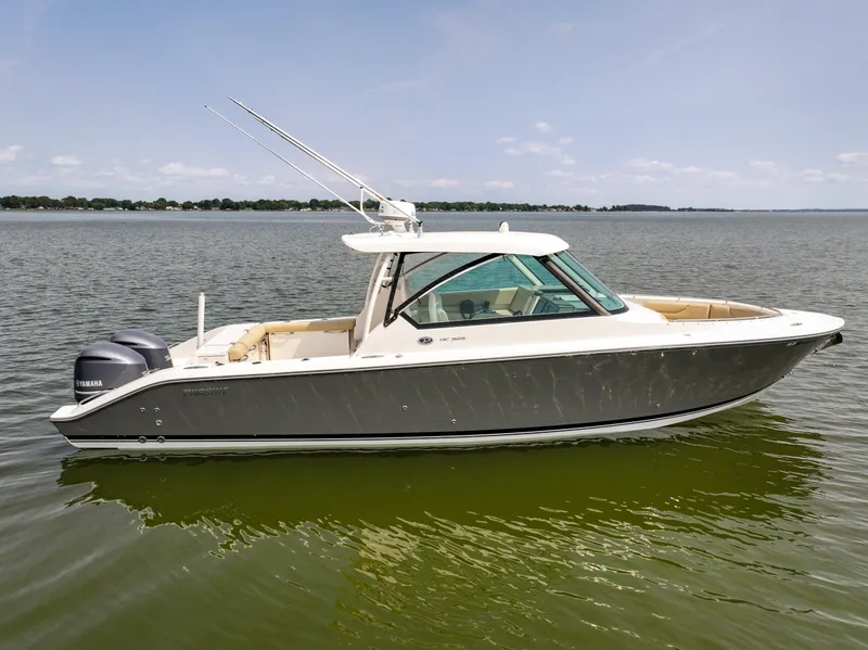 Slide: The Image of A 2015 Pursuit DC 325 Dual Console boat on calm water. It features a sleek design and twin outboard engines. - 8
