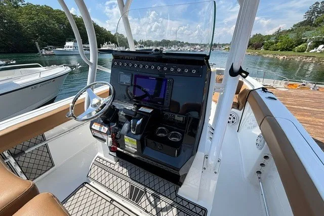 Slide: The Image of 2021 Wellcraft 242 Fisherman boat cockpit with modern controls, docked by a scenic waterfront. - 10