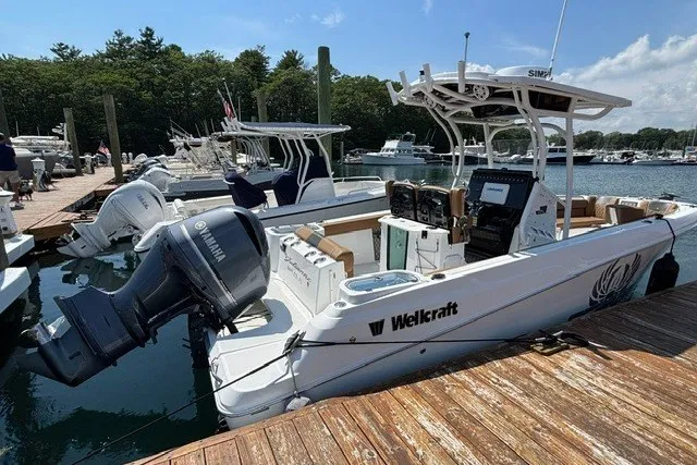 Slide: The Image of 2021 Wellcraft 242 Fisherman boat docked, featuring Yamaha outboard motor, in a scenic marina. - 2
