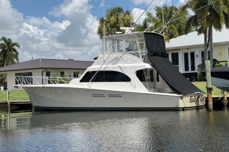 Slide: The Image of 2007 Post 50 Convertible yacht docked by a waterfront home, under a partly cloudy sky. - 1