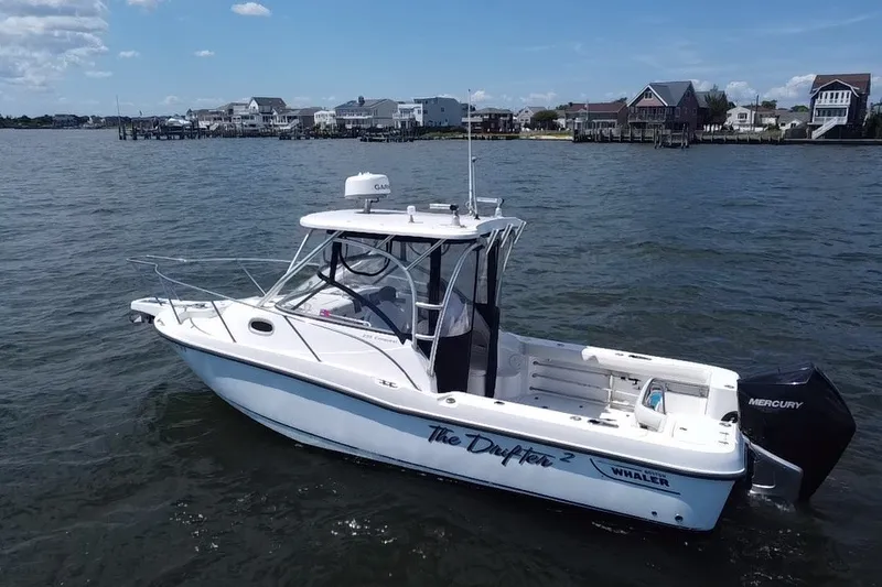 The Image of 2005 Boston Whaler 235 Conquest boat on water, with coastal houses in the background. - 1