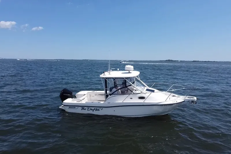 Slide: The Image of 2005 Boston Whaler 235 Conquest boat on open water under clear blue sky. - 7