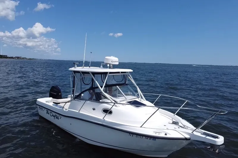 Slide: The Image of 2005 Boston Whaler 235 Conquest boat on open water under clear blue sky. - 2
