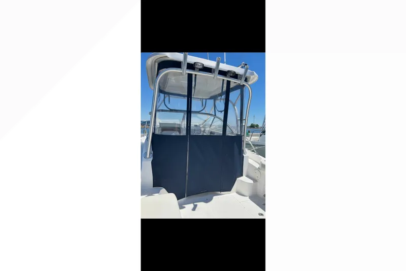 Slide: The Image of 2005 Boston Whaler 235 Conquest boat with blue canopy and clear windshield. - 13
