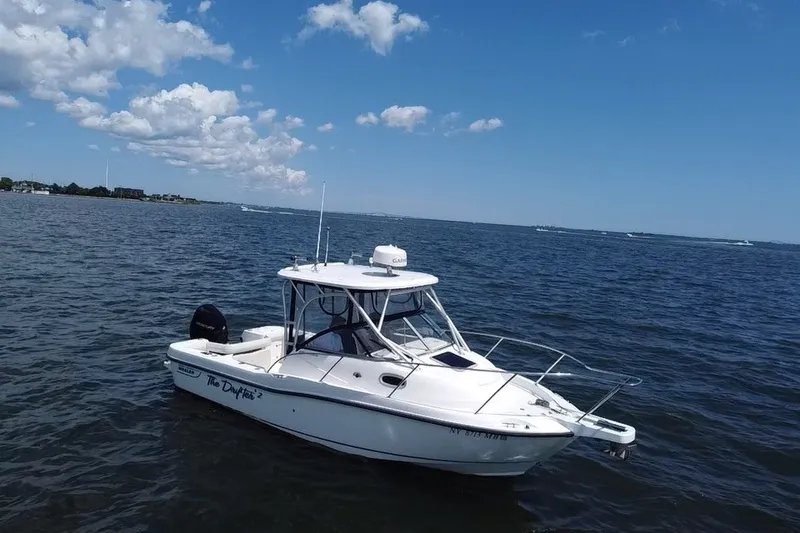 Slide: The Image of 2005 Boston Whaler 235 Conquest boat on open water under a clear blue sky. - 6