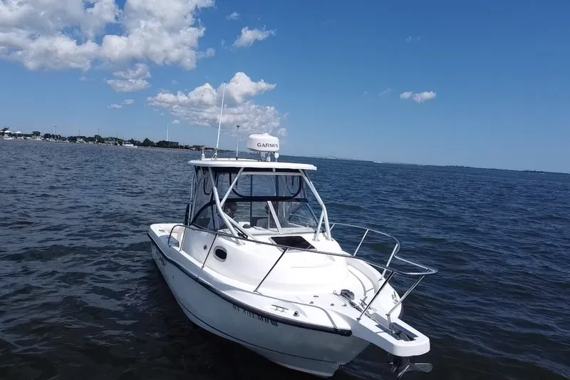 Slide: The Image of 2005 Boston Whaler 235 Conquest boat on calm water under a clear sky. - 10