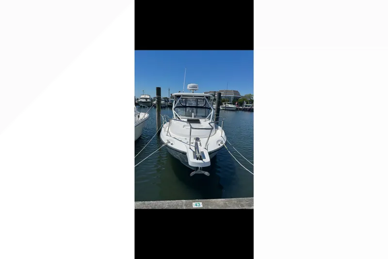 Slide: The Image of 2005 Boston Whaler 235 Conquest boat docked in a marina under clear blue skies. - 15