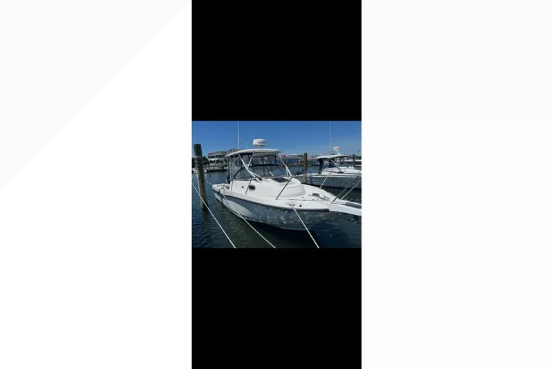 Slide: The Image of 2005 Boston Whaler 235 Conquest boat docked at marina under clear blue sky. - 17