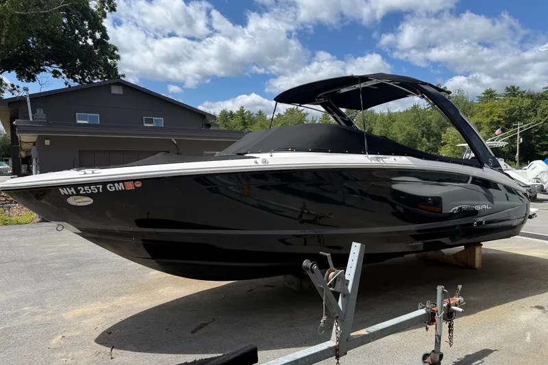 Slide: The Image of 2021 Regal LS6 boat on trailer, black exterior, parked outdoors under blue sky. - 2