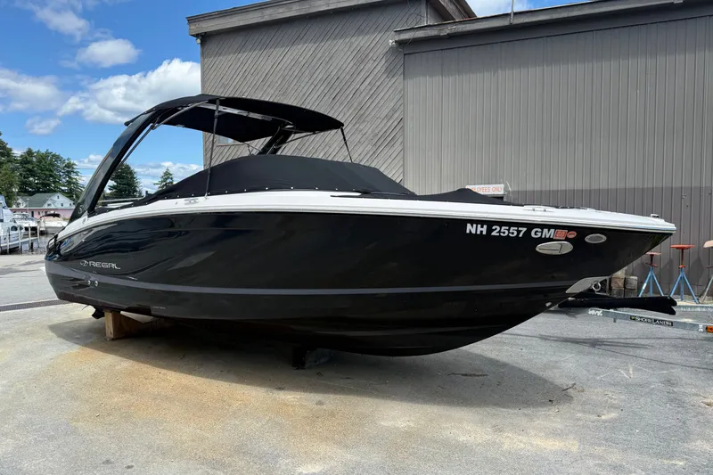 The Image of 2021 Regal LS6 boat with black hull, docked outdoors under a clear sky. - 0