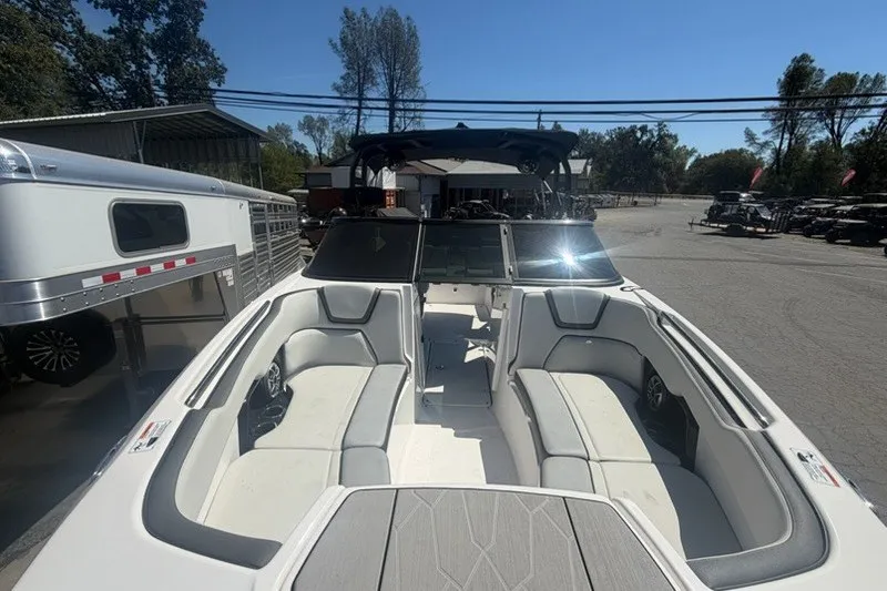 Slide: The Image of 2022 Yamaha Boats 252XE with spacious seating, parked outdoors under clear blue sky. - 11
