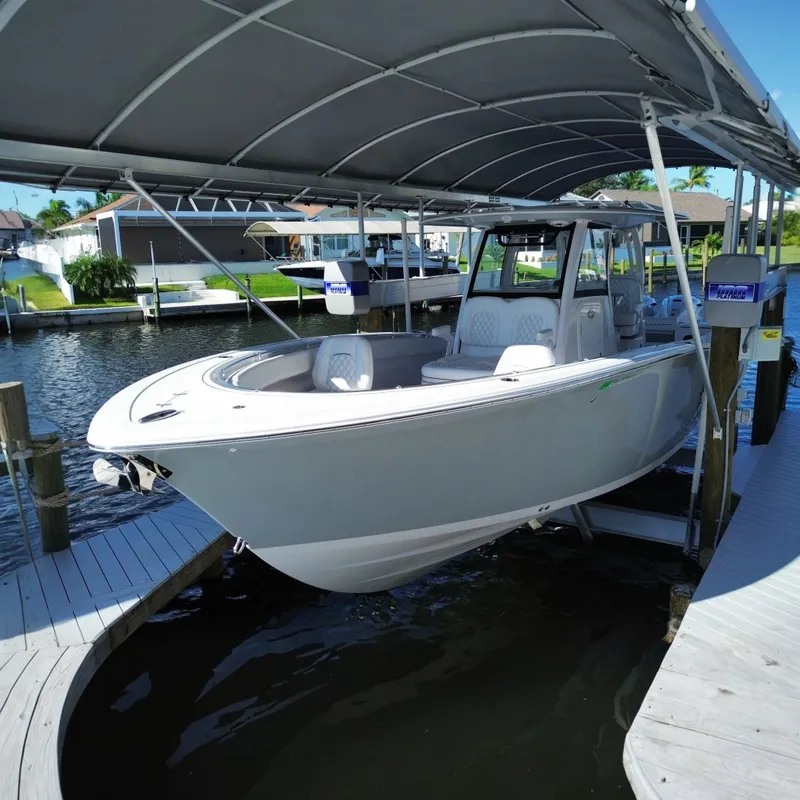 The Image of 2025 Sportsman Open 322 Center Console boat docked under a canopy. - 0