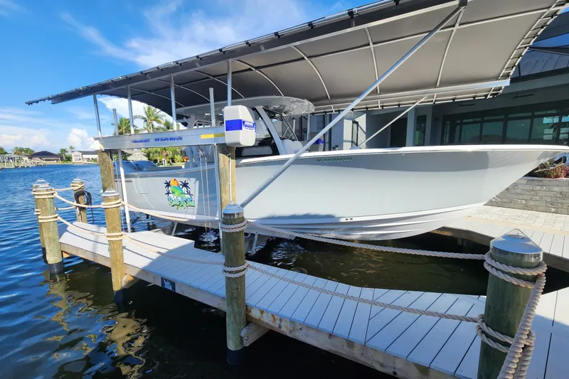 Slide: The Image of 2025 Sportsman Open 322 Center Console boat docked under a canopy on a sunny day. - 14