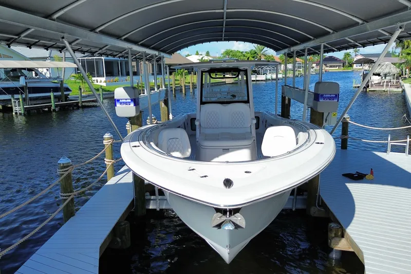 Slide: The Image of 2025 Sportsman Open 322 Center Console boat docked under a canopy on a sunny day. - 2