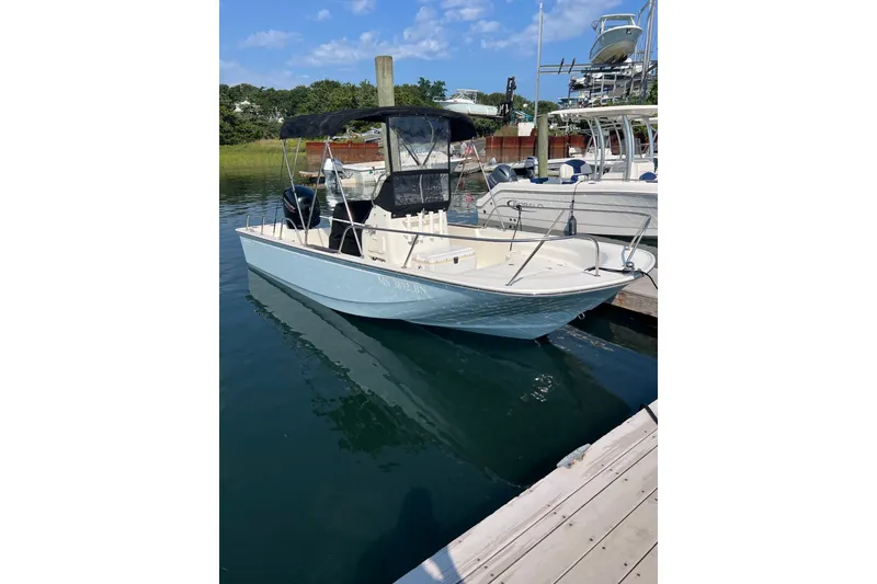 Slide: The Image of 2021 Boston Whaler 190 Montauk boat docked in a marina under a clear blue sky. - 2