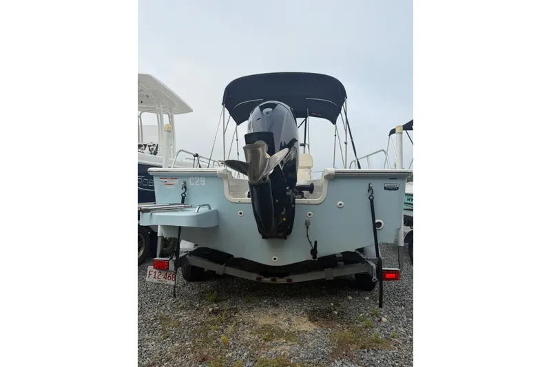 Slide: The Image of 2021 Boston Whaler 190 Montauk boat, rear view with outboard motor, parked on gravel. - 11