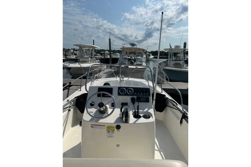 Slide: The Image of 2021 Boston Whaler 190 Montauk boat interior with steering wheel and controls at marina. - 5