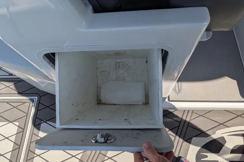 Slide: The Image of Open storage compartment on 2022 Encore Boat Works 28, showing interior space and latch mechanism. - 19