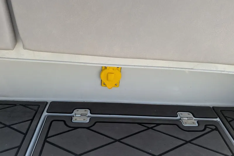 Slide: The Image of Yellow outlet on 2022 Encore Boat Works 28 interior wall above deck flooring. - 15