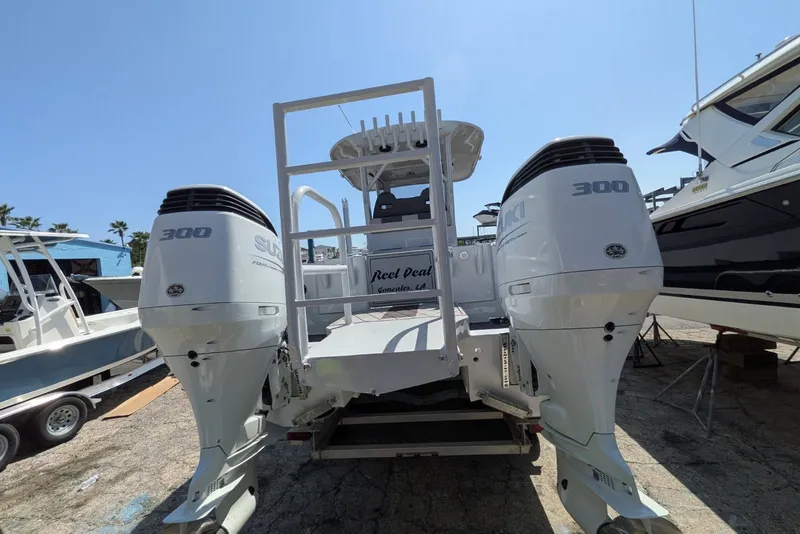 Slide: The Image of 2022 Encore Boat Works 28 with dual Suzuki 300 engines, docked under clear blue sky. - 4