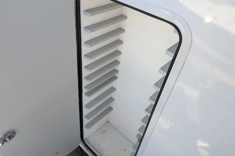 Slide: The Image of Open storage compartment on 2022 Encore Boat Works 28, featuring interior shelving. - 16