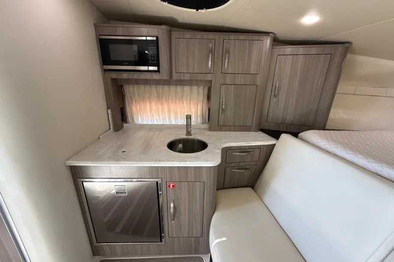 Slide: The Image of 2019 Regal 33 XO yacht interior with kitchenette, featuring microwave, sink, and cabinetry. - 21