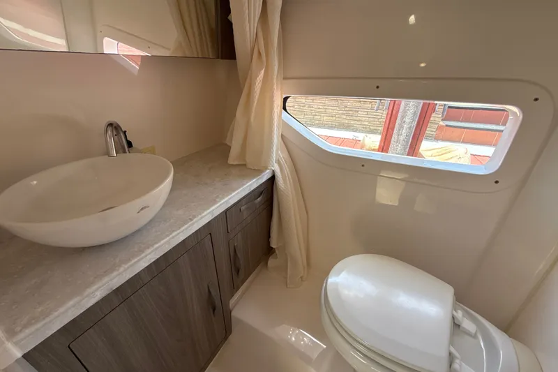 Slide: The Image of 2019 Regal 33 XO yacht bathroom with modern sink, toilet, and window. - 29