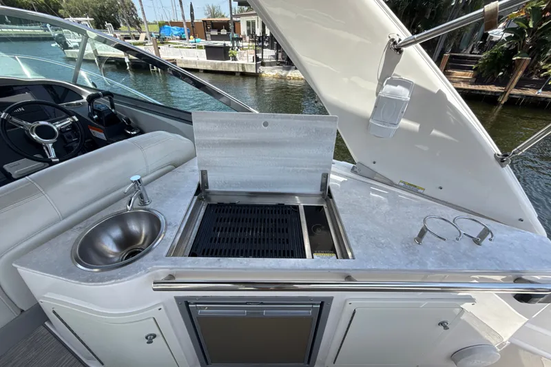 Slide: The Image of 2019 Regal 33 XO yacht kitchenette with sink and grill by the water. - 11