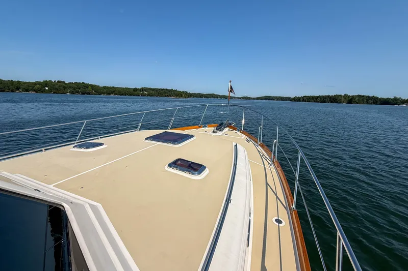 Slide: The Image of 2008 Grand Banks 45 Eastbay SX yacht cruising on a serene lake under clear blue skies. - 48