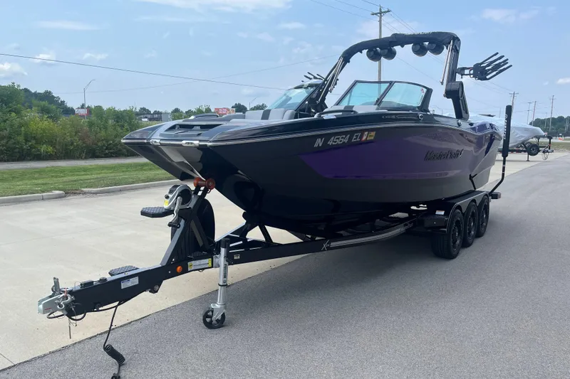 Slide: The Image of 2023 MasterCraft X24 boat on trailer, parked on a road, showcasing sleek design. - 5