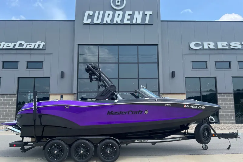Slide: The Image of 2023 MasterCraft X24 boat in purple, parked outside dealership. - 2