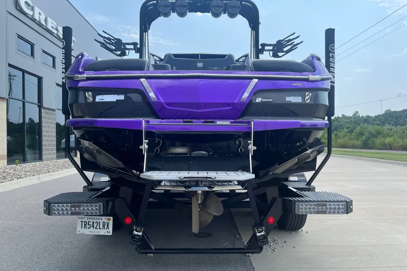 Slide: The Image of 2023 MasterCraft X24 boat in vibrant purple, rear view, parked outdoors. - 7