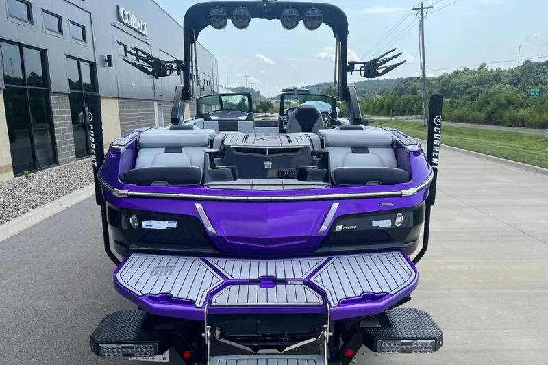 Slide: The Image of 2023 MasterCraft X24 boat with purple detailing, parked near a building. - 8