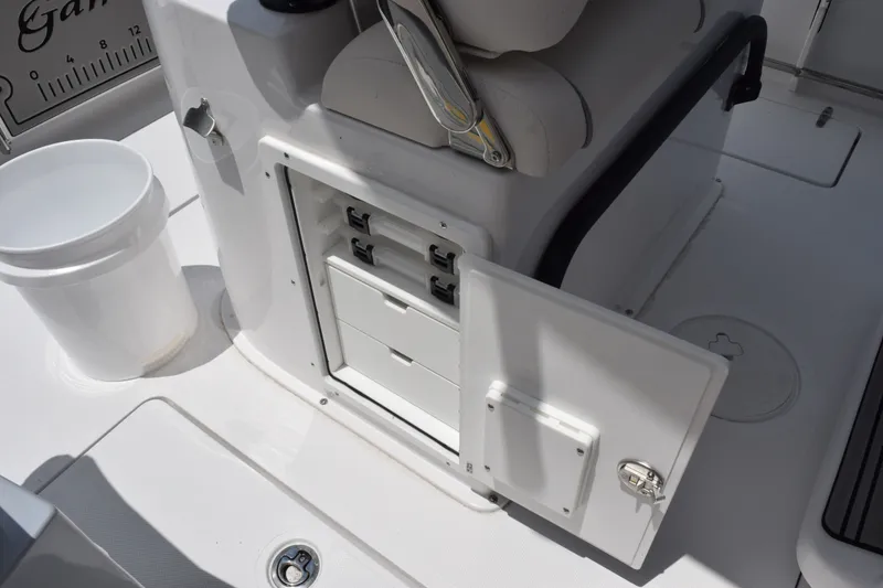 Slide: The Image of 2027 Sea Hunt Gamefish 25 boat interior with open storage compartment and white bucket. - 14