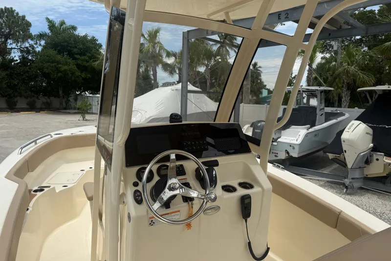 Slide: The Image of 2024 Scout 215 XSF boat interior with steering wheel and console, parked outdoors. - 7