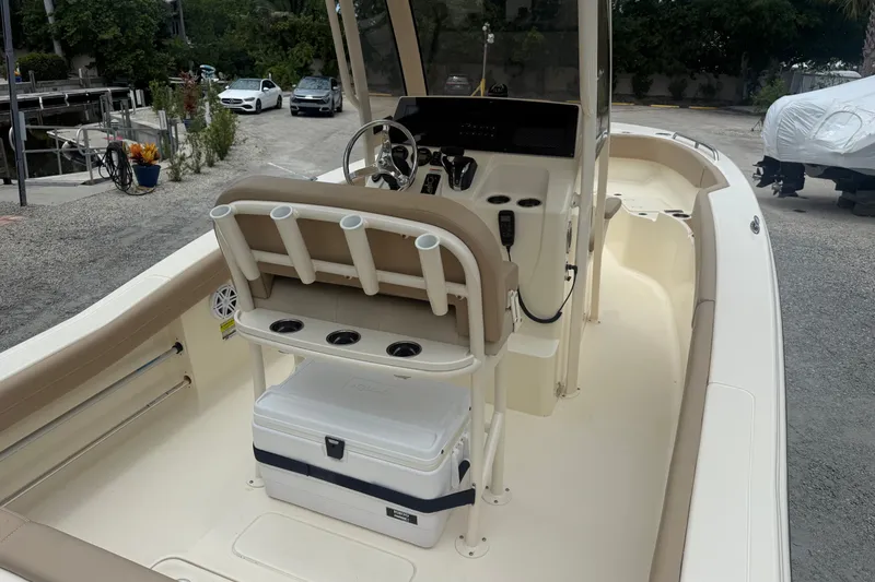 Slide: The Image of 2024 Scout 215 XSF boat interior with helm, seating, and cooler on a sunny day. - 5