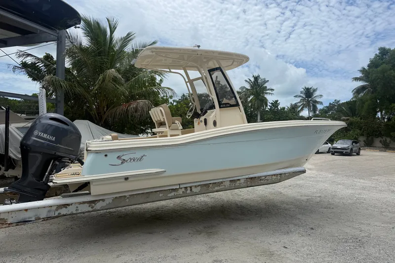 Slide: The Image of 2024 Scout 215 XSF boat with Yamaha engine on trailer, surrounded by palm trees. - 1